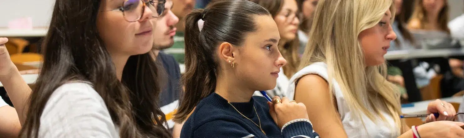 Trois étudiantes en premier plan qui écoutent un cours d'heip